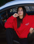Modelo sentado en coche con sudadera urbana en color rojo con detalles bordados
